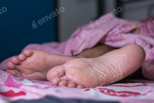 Preview: Sleeping woman feet under blanket.