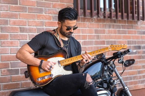 Preview: Man Playing Guitar on Motorcycle in Urban Setting