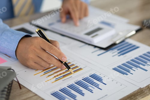 Preview: Businessman pointing at chart in document analyzing financial reports.