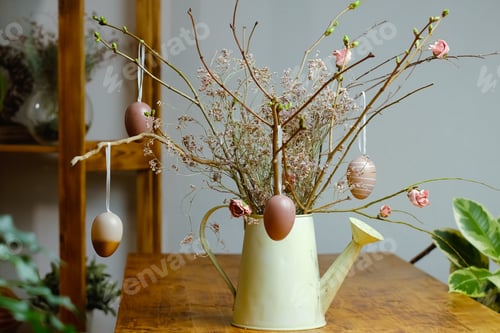 Preview: DIY Easter floral composition with hanged eggs on spring plant twigs.