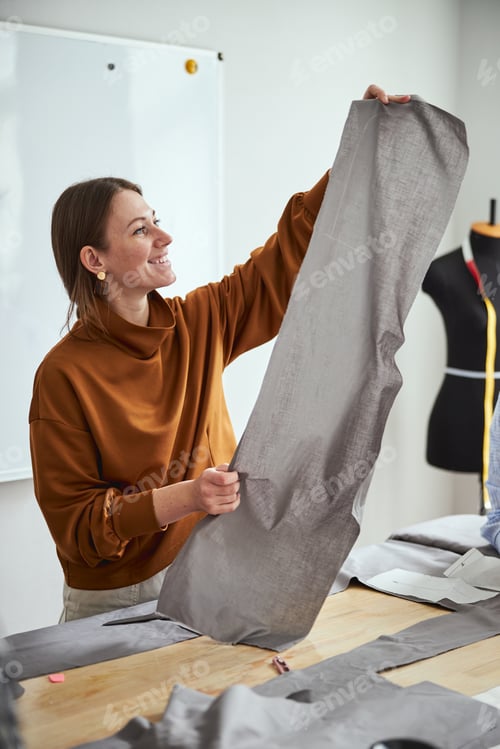 Preview: Female dressmaker raising fabric sheet in hands