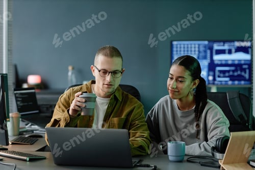 Preview: Team of Two Positive Programmers Using Laptop Discussing Code Debugging in Office