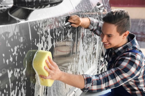 Preview: Worker cleaning automobile with sponge at car wash