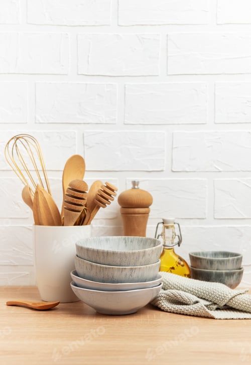 Preview: Kitchen utensils, bowls and ingredients resting on wooden countertop by white brick wall