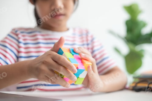 Preview: Asian little cute girl holding Rubik's cube in her hands. Rubik's cube is a game that increases the