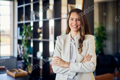 Preview: Portrait of a smiling brunette woman, dressed in a suit, posing for the camera.