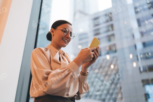Preview: Happy female browsing cellphone standing near window