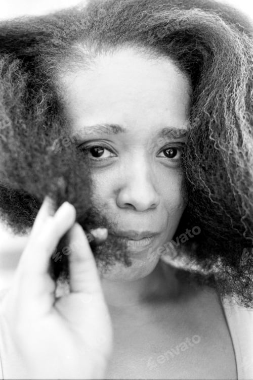 Preview: Young woman playing with curly hair monochrome portrait