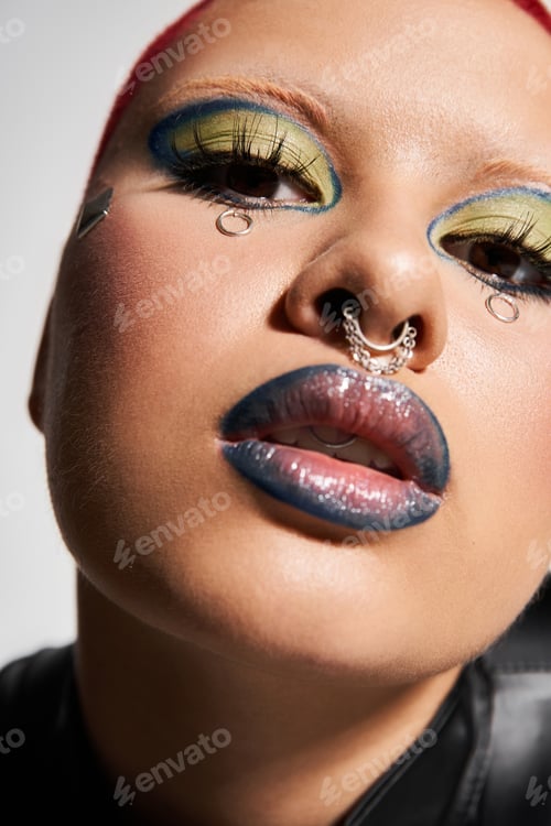 Preview: Bold young woman with short pink hair and striking makeup showcases unique style in a studio