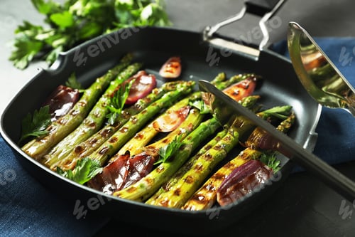 Preview: Delicious grilled vegetables with parsley in pan and tongs on table, closeup