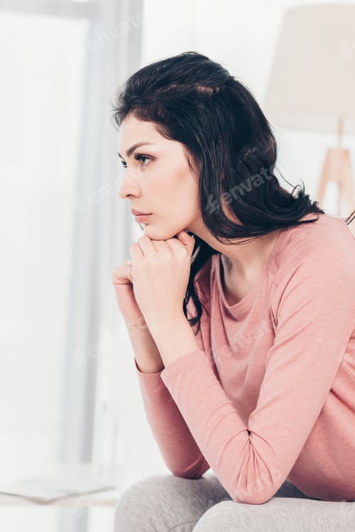 Preview: beautiful upset woman sitting and propping chin with hands at home