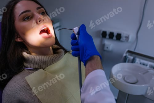 Preview: female patient in dental chair open mouth. Dentist's hands with