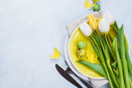 Preview: Easter table setting with tulips, quail eggs and cutlery. Spring Holidays Stone Blue background.