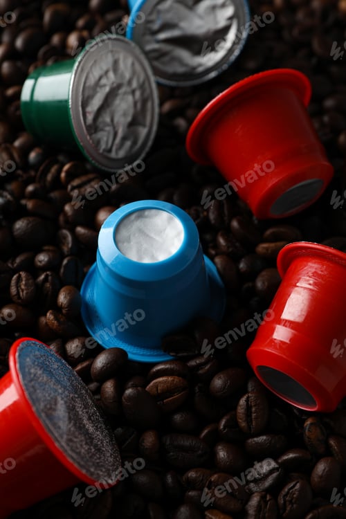 Preview: Colored coffee capsules on coffee beans, close up