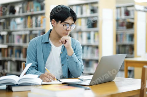 Preview: Young university student using laptop for online learning, searching and learning at library.