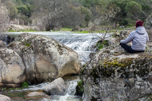 Preview: Closeup shot of a female relaxing in nature next to a waterfall in the river