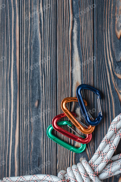 Preview: Isolated photo of climbing equipment. Part of carabiner lying on the wooden table