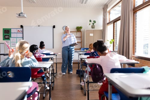 Preview: In school, female teacher instructing diverse group of students in classroom setting