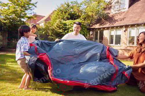 Preview: Asian Family In Garden At Home Putting Up Tent For Camping Trip Together
