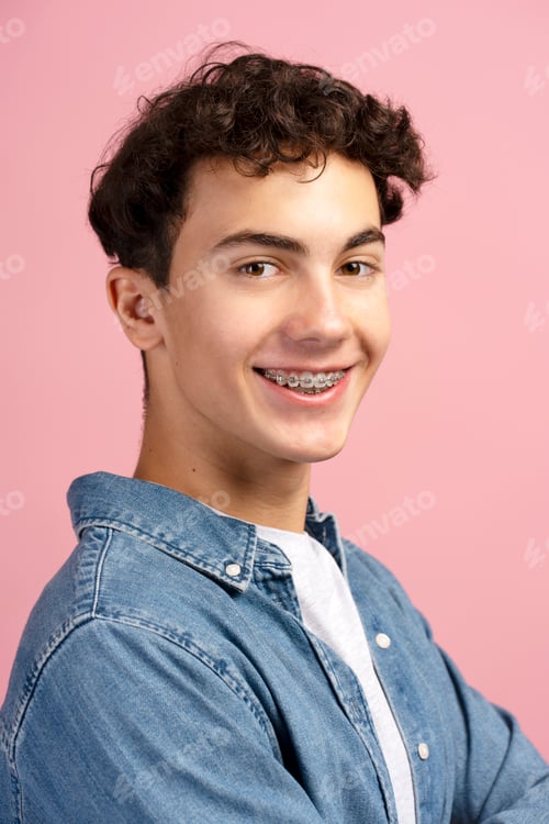 Preview: Closeup, happy, attractive teenager, boy with braces wearing casual clothes on pink background