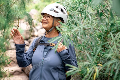 Preview: Senior woman with backpack and helmet enjoying trekking day on mountain