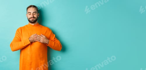 Preview: Handsome man feeling nostalgic, holding hands on heart and daydreaming, remember or imaging