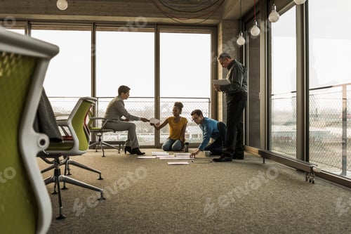 Preview: Businesspeople looking at documents on office floor