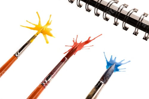 Preview: close up view of brushes in paint and splashes on paper