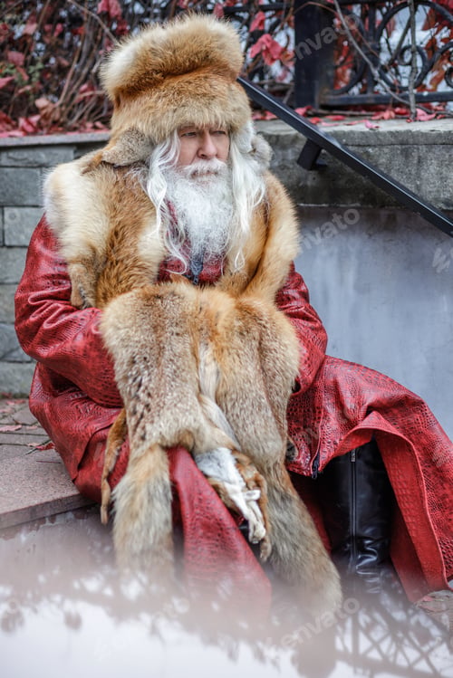 Preview: An elderly gray-haired man with a lush moustache and beard sits on the steps of the stairs and looks