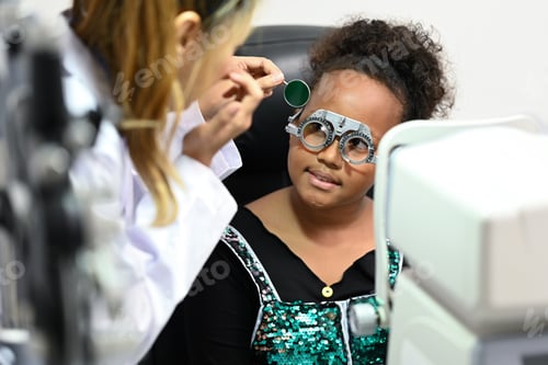 Preview: Ophthalmologist testing vision or sight of cute little girl in modern ophthalmology clinic.