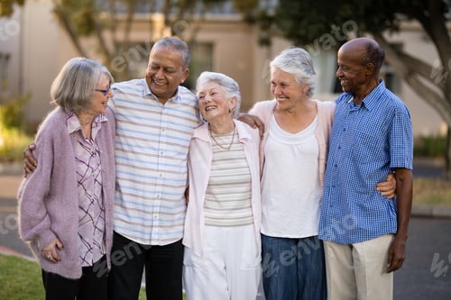 Preview: Smiling senior friends standing with arms around