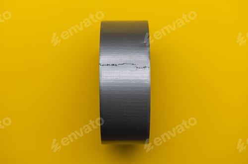 Preview: Duck tape on yellow background. Roll of tape closeup view.