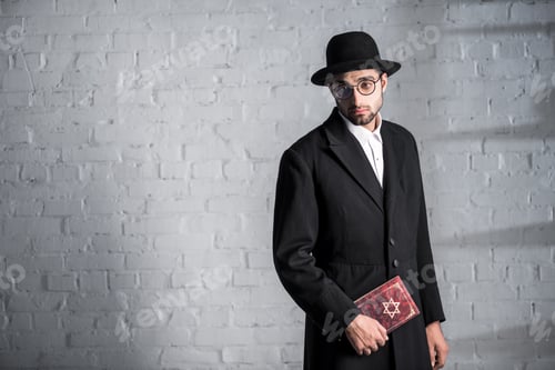 Preview: handsome and sad jewish man in glasses holding tanakh