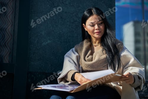 Preview: Beautiful woman studying documents on the street