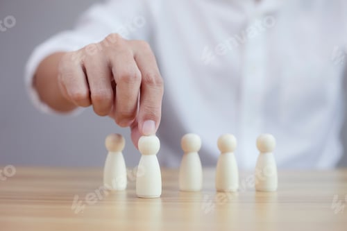 Preview: Businessman hands chooses best successful people wood model team.