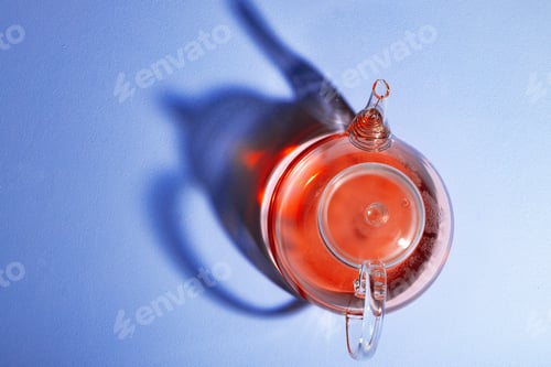 Preview: Glass teapot with fruit tea on blue background