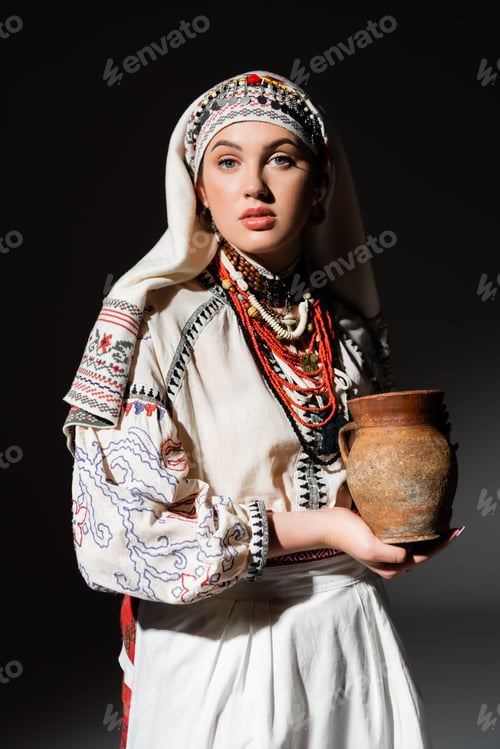 Preview: portrait of young ukrainian woman in traditional clothing with ornament holding clay pot on black