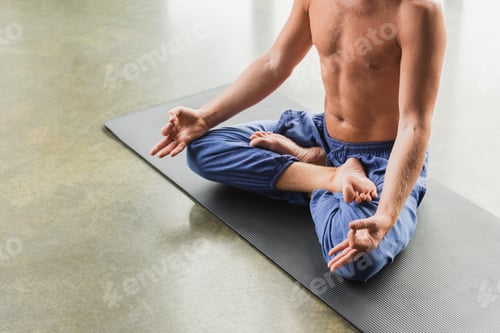 Preview: cropped view of man in blue pants sitting in lotus pose and doing gyan mudra