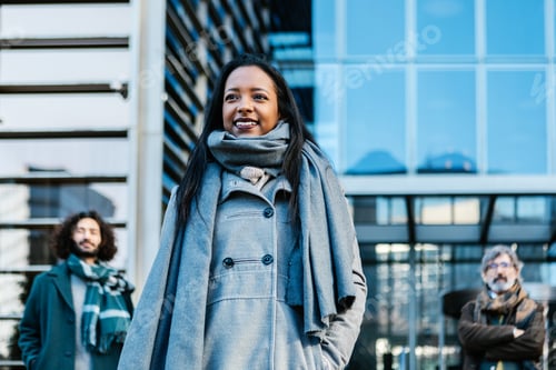 Preview: Successful young adult businesswoman standing with business colleagues outdoors.