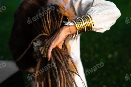 Preview: A woman arranges her dreadlocks