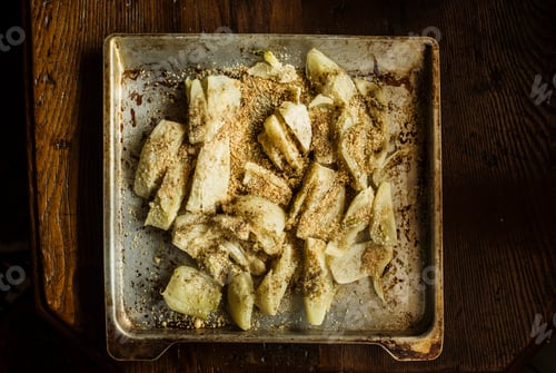 Preview: A rustic baking tray with seasoned potato wedges ready for the oven.