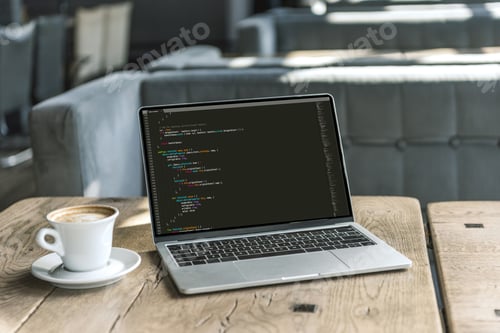Preview: cup of coffee and laptop with program code on screen on rustic wooden table at cafe