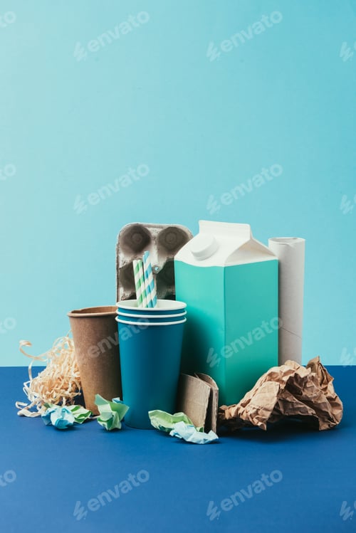 Preview: close up view of arranged cardboard and paper disposable garbage on blue background