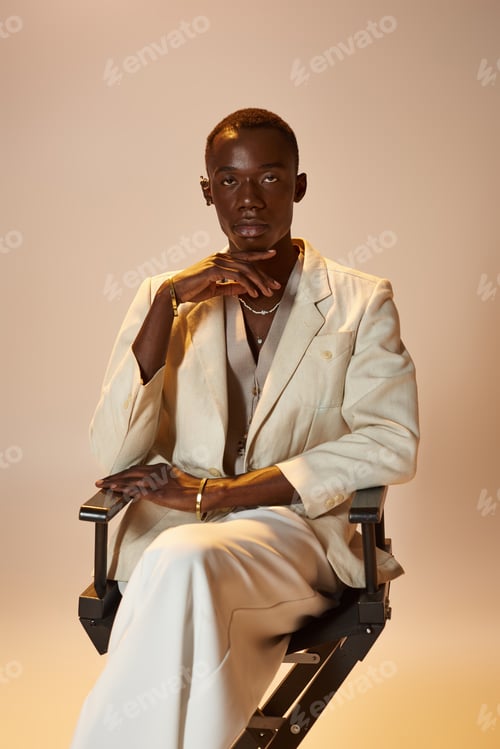 Preview: Stylish young african american man confidently poses in chic attire against a soft backdrop