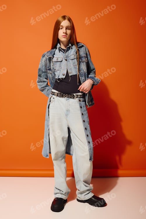 Preview: Young man with long red hair expressing emotions against a vibrant orange backdrop
