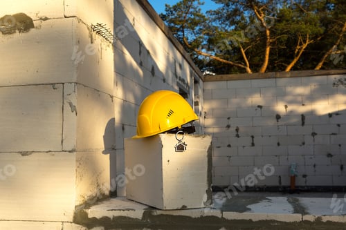 Preview: Construction yellow hardhat and key to house on window of housing made of blocks