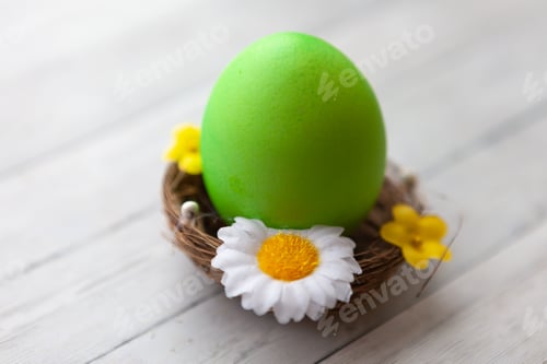 Preview: Painted Easter egg in a basket on a light wooden background, top view