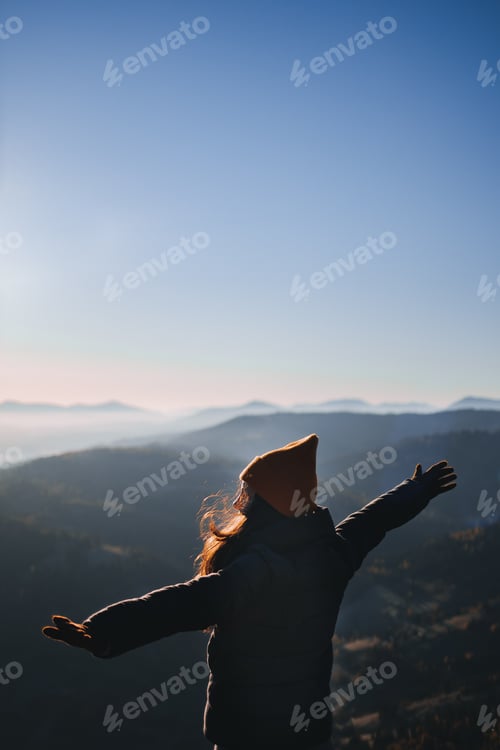 Preview: Girl from back view is looking at the mountains morning view. Person from behind