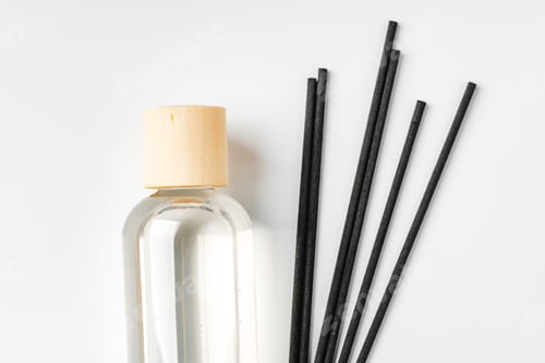 Preview: A minimalist display of essential oil and black diffuser sticks on a clean white background