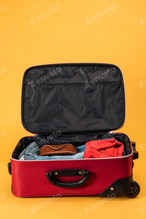 Preview: case and clothes in travel bag on yellow background